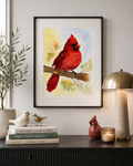 watercolor cardinal painting by Paula A Chavers displayed in a modern neutral interior with bird decor, books, lamp, and soft natural lighting
