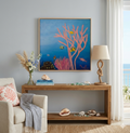 Coastal living room featuring original acrylic ocean painting with coral and colorful fish by Paula A Chavers displayed above a light sofa with beach-inspired decor